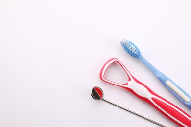 Photo of New tongue cleaner, toothbrush and dental mirror on white background, top view