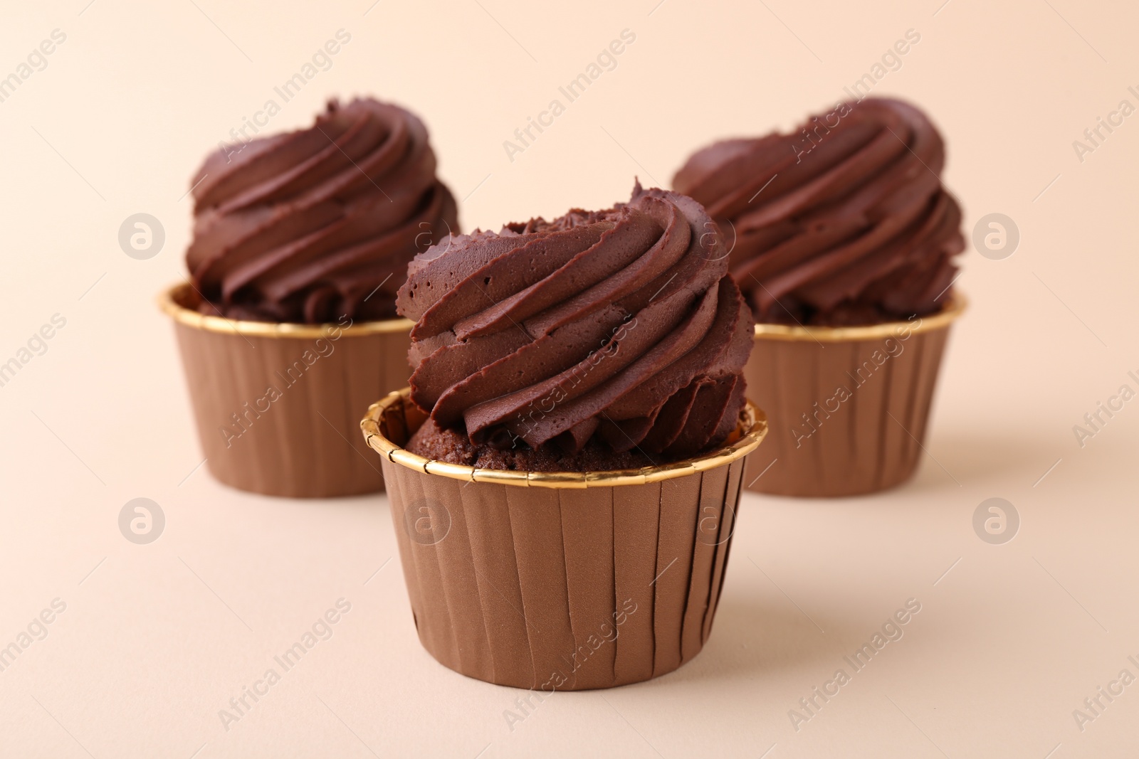 Photo of Delicious chocolate cupcakes on beige background, closeup