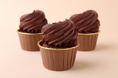 Delicious chocolate cupcakes on beige background, closeup