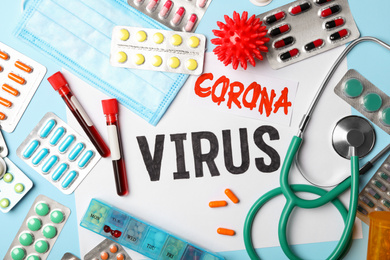 Photo of Flat lay composition with phrase CORONA VIRUS and medicines on light blue background