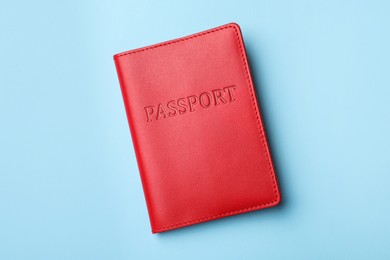 Passport in red leather case on light blue background, top view