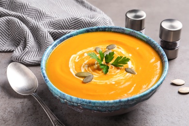 Bowl with tasty pumpkin soup served on gray table