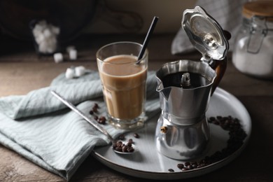 Photo of Brewed coffee in moka pot, glass of drink and beans on wooden table