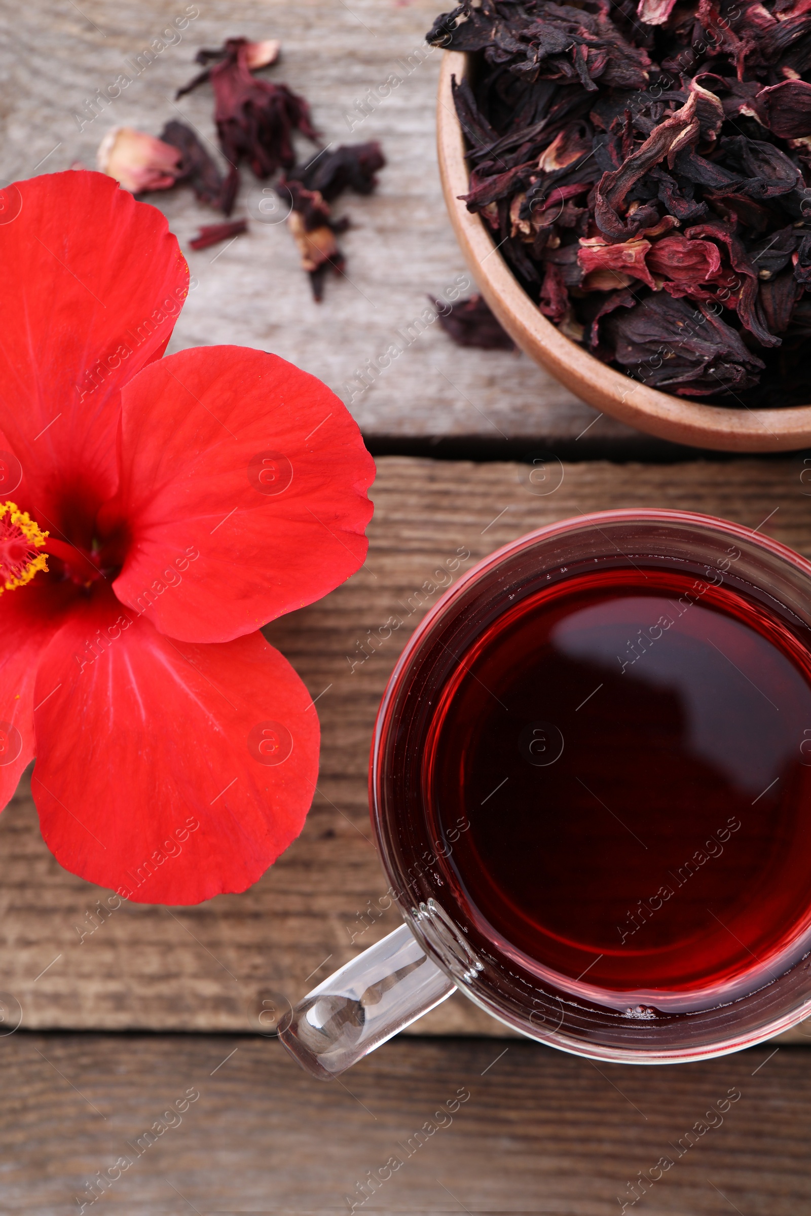 Photo of Delicious hibiscus tea and flowers on wooden table, flat lay