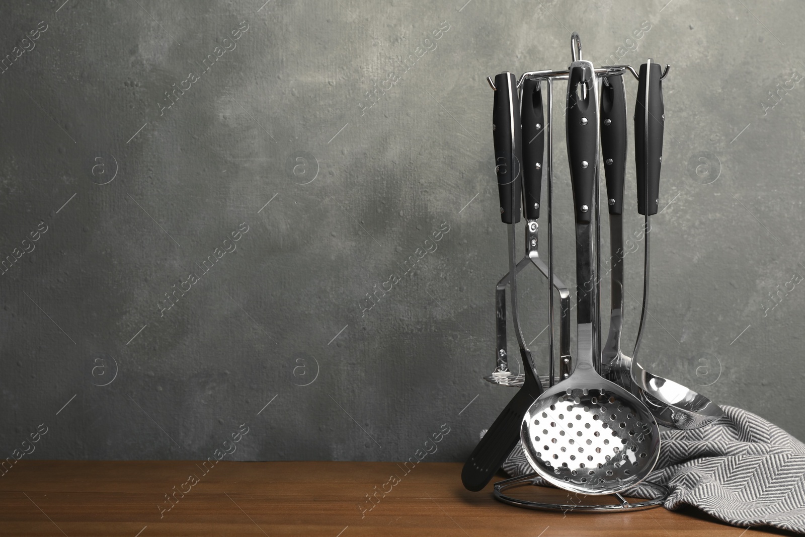 Photo of Holder with clean kitchen utensils and napkin on table. Space for text