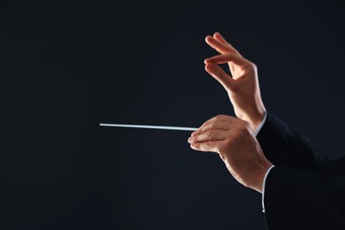 Photo of Professional conductor with baton on black background, closeup. Space for text