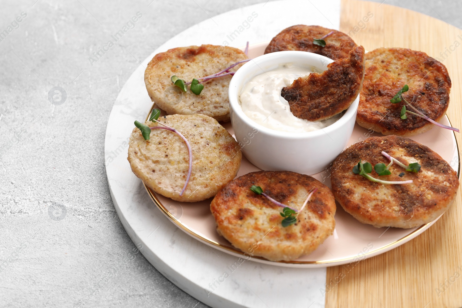 Photo of Delicious vegan cutlets and sauce on light grey table, space for text