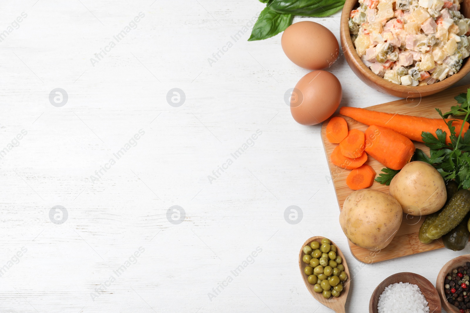 Photo of Delicious salad Olivier and ingredients on white wooden table, flat lay. Space for text