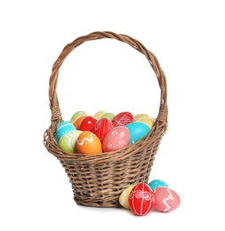 Photo of Wicker basket with painted Easter eggs on white background