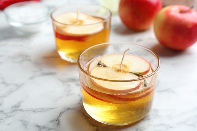 Photo of Handmade candles with apple slices on marble table