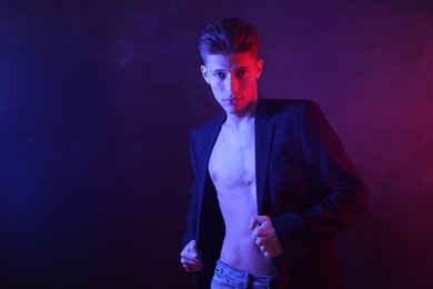 Photo of Sexy young man on dark background in neon lights. Space for text