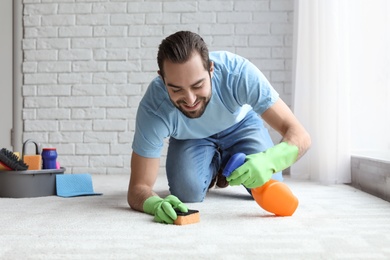 Young man cleaning carpet at home