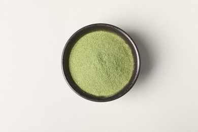 Photo of Wheat grass powder in bowl on light table, top view