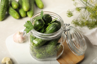 Photo of Pickling jar with fresh cucumbers on light table, closeup