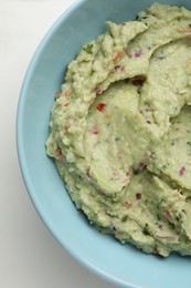 Photo of Bowl with delicious fresh guacamole on white table, top view