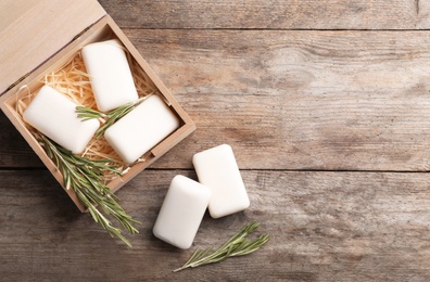 Photo of Flat lay composition with soap bars, rosemary and space for text on wooden background