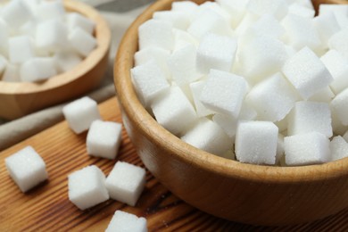 Photo of White sugar cubes on wooden table, closeup