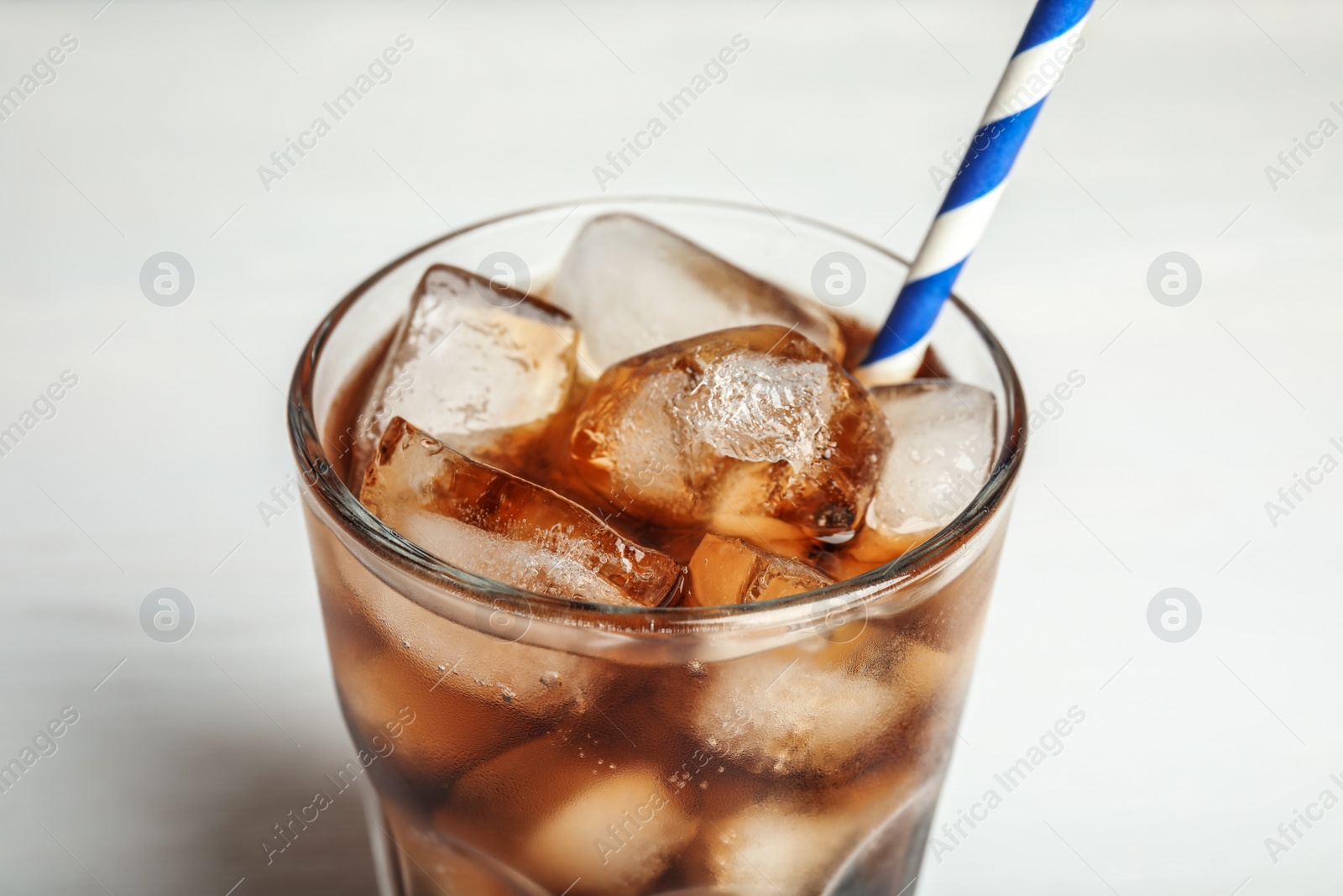 Photo of Glass of refreshing soda drink with ice cubes and straw on white background, closeup