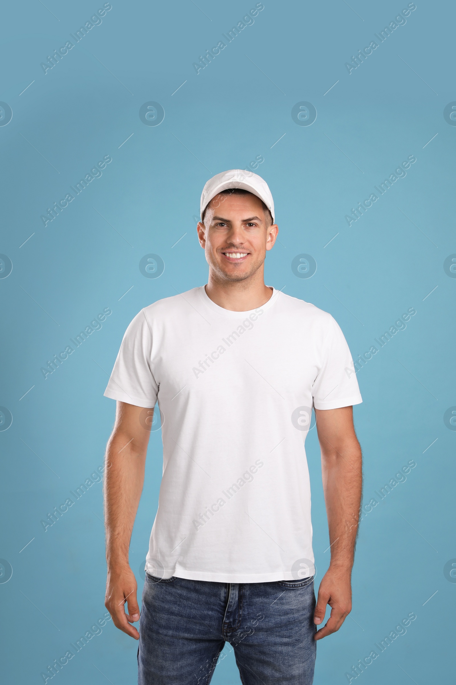 Photo of Happy man in white cap and tshirt on light blue background. Mockup for design