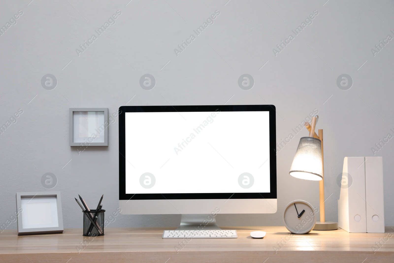 Photo of Comfortable workplace with blank computer display on desk near light grey wall. Space for text