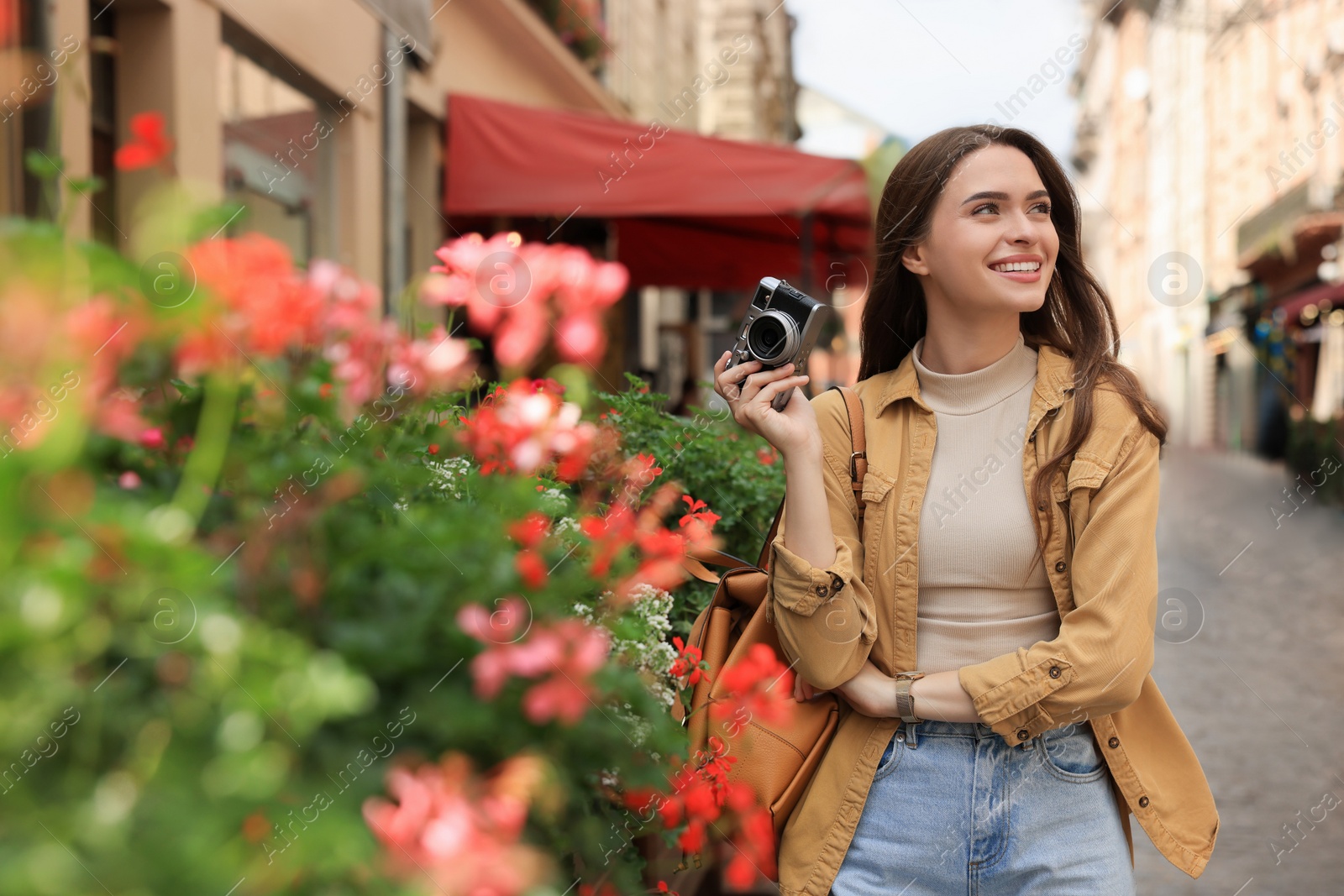 Photo of Young woman with camera on city street. Interesting hobby