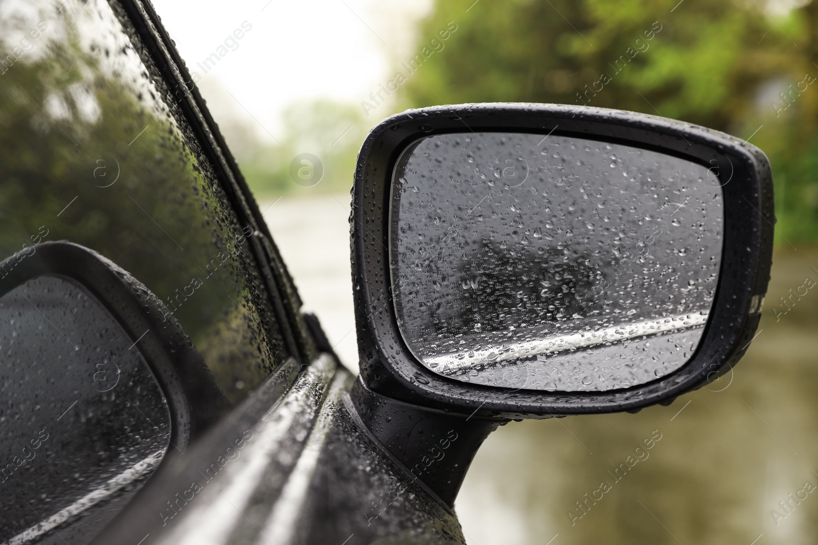 Photo of Closeup of car side rear view mirror with rain drops