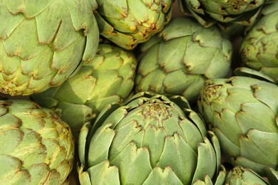 Many fresh raw artichokes as background, top view