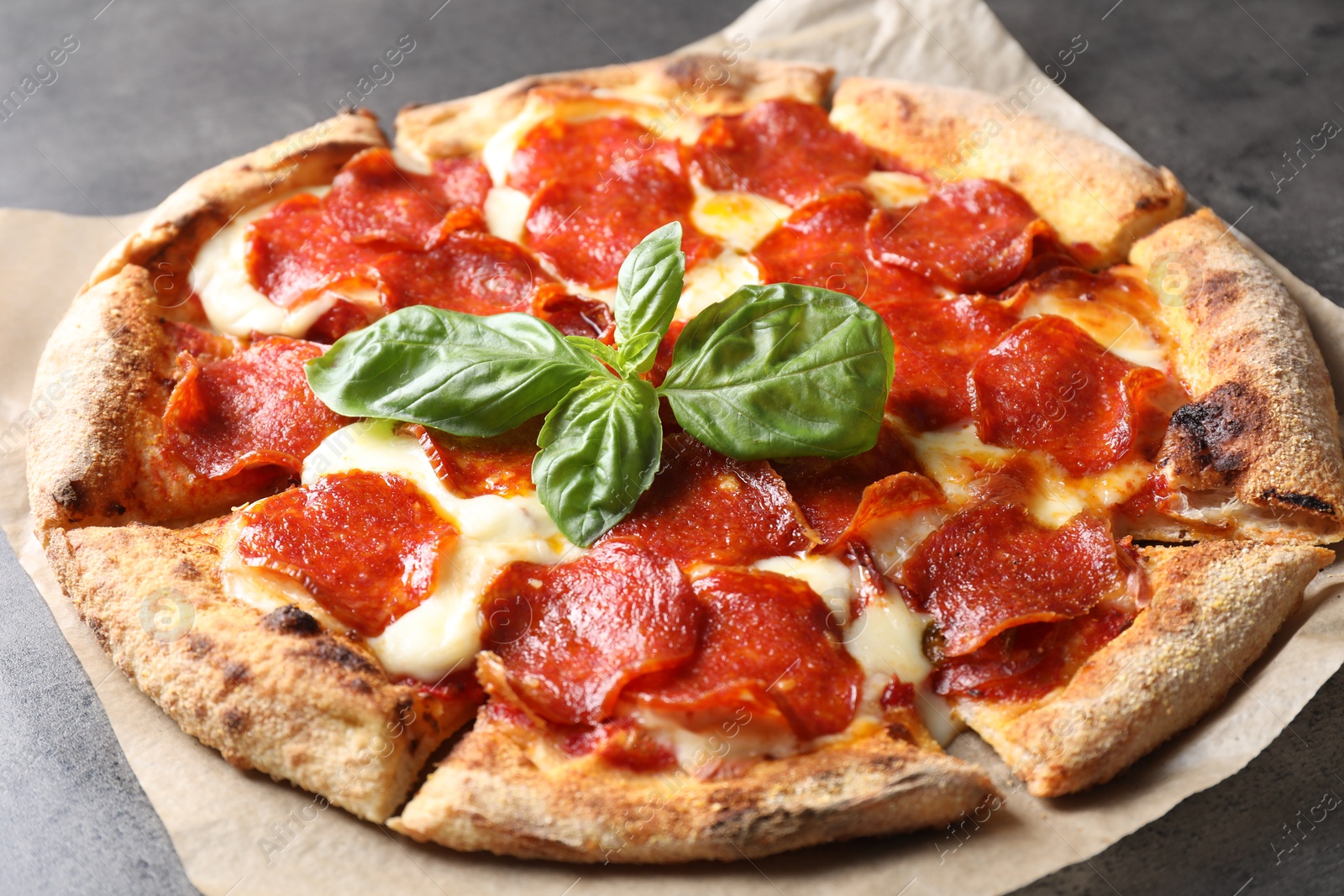 Photo of Tasty pepperoni pizza with basil on grey table