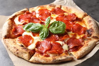 Tasty pepperoni pizza with basil on grey table