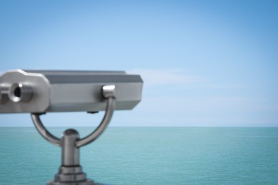 Photo of Metal tower viewer and picturesque view of sea with boat. Mounted binoculars