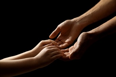 Photo of Man with child on black background, closeup of hands
