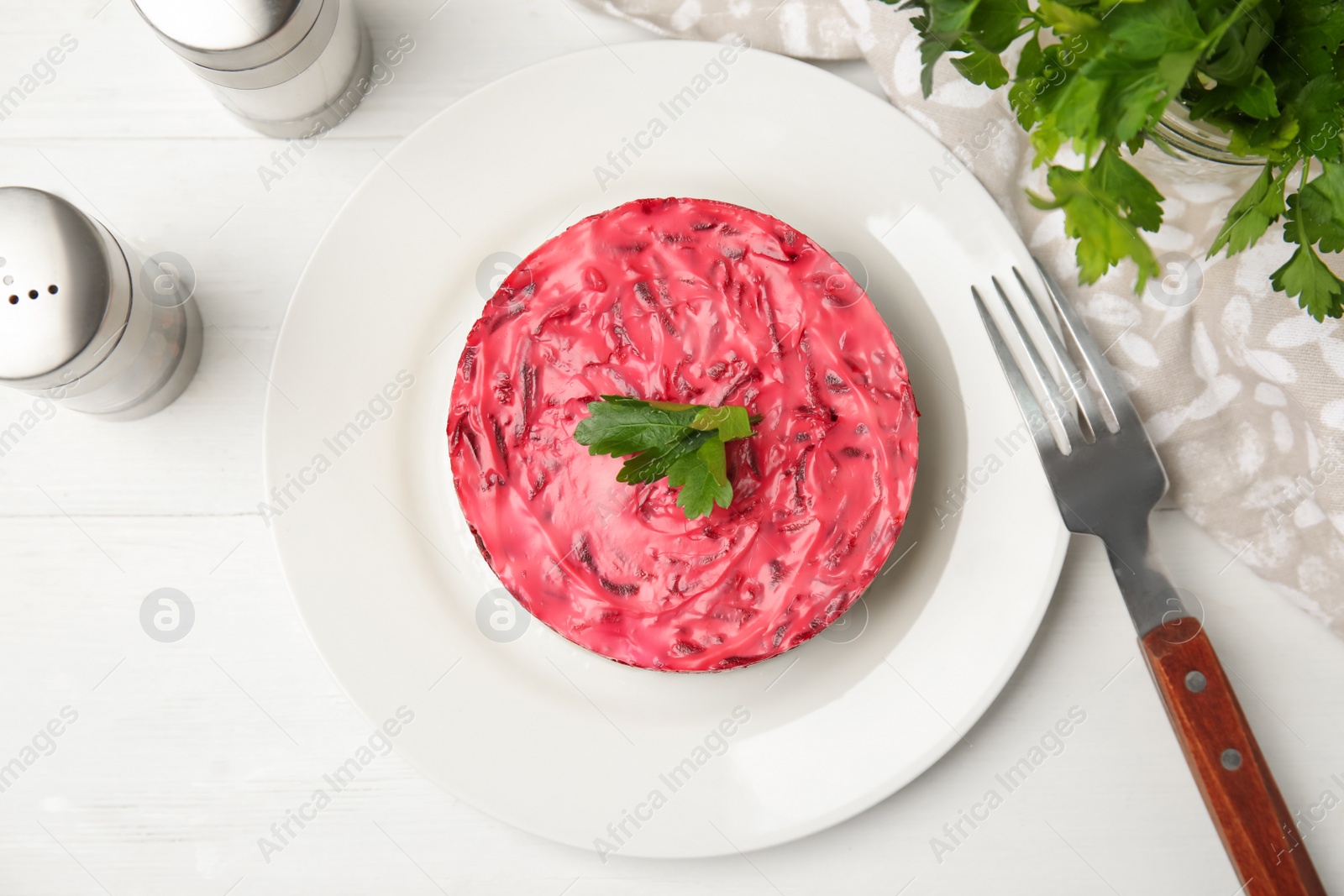 Photo of Herring under fur coat served on white wooden table, flat lay. Traditional russian salad