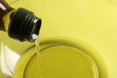 Photo of Pouring cooking oil from bottle into bowl, closeup