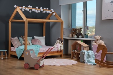 Stylish child room interior with wooden bed in shape of house and toys