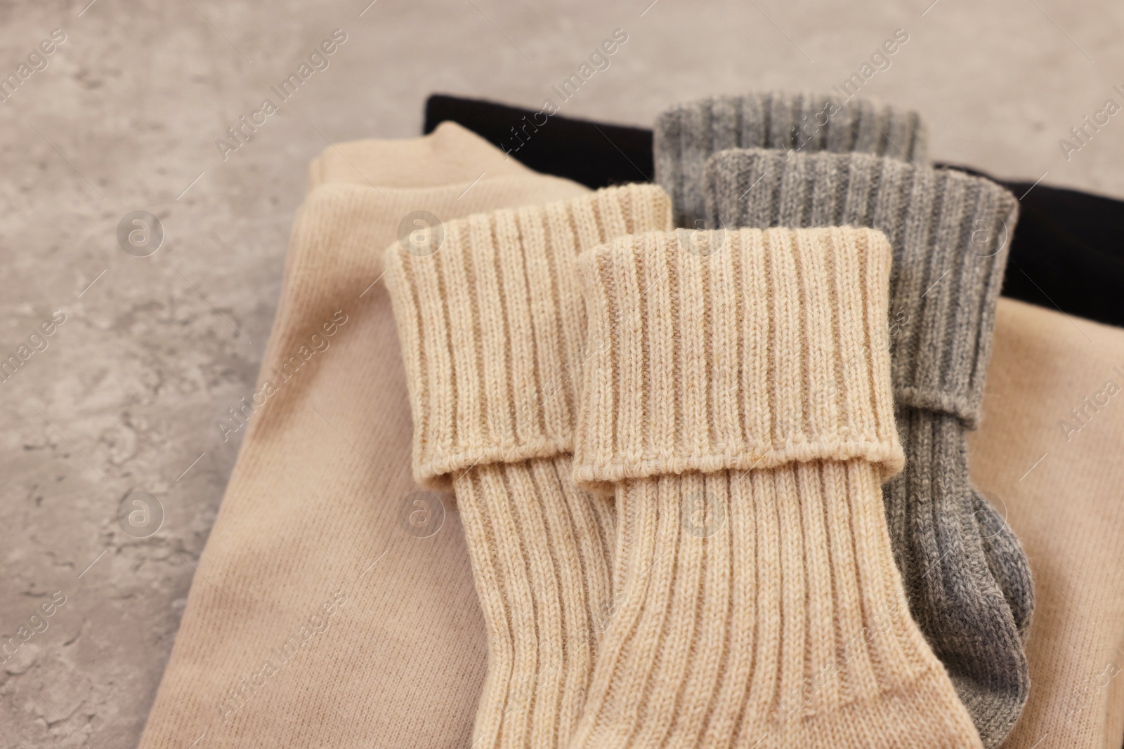 Photo of Soft comfortable socks and sweaters on grey table, above view. Space for text