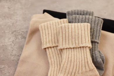 Photo of Soft comfortable socks and sweaters on grey table, above view. Space for text