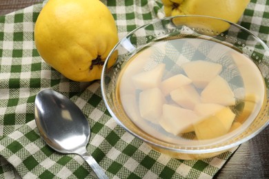 Photo of Delicious quince drink in glass bowl, fresh fruits and spoon on table, closeup