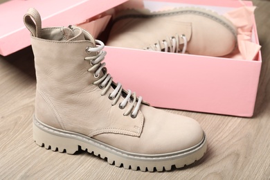 Pair of stylish boots and box on wooden background