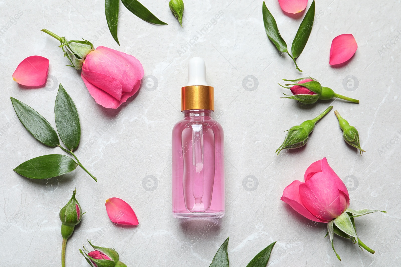 Photo of Flat lay composition with fresh flowers and bottle of rose essential oil on table