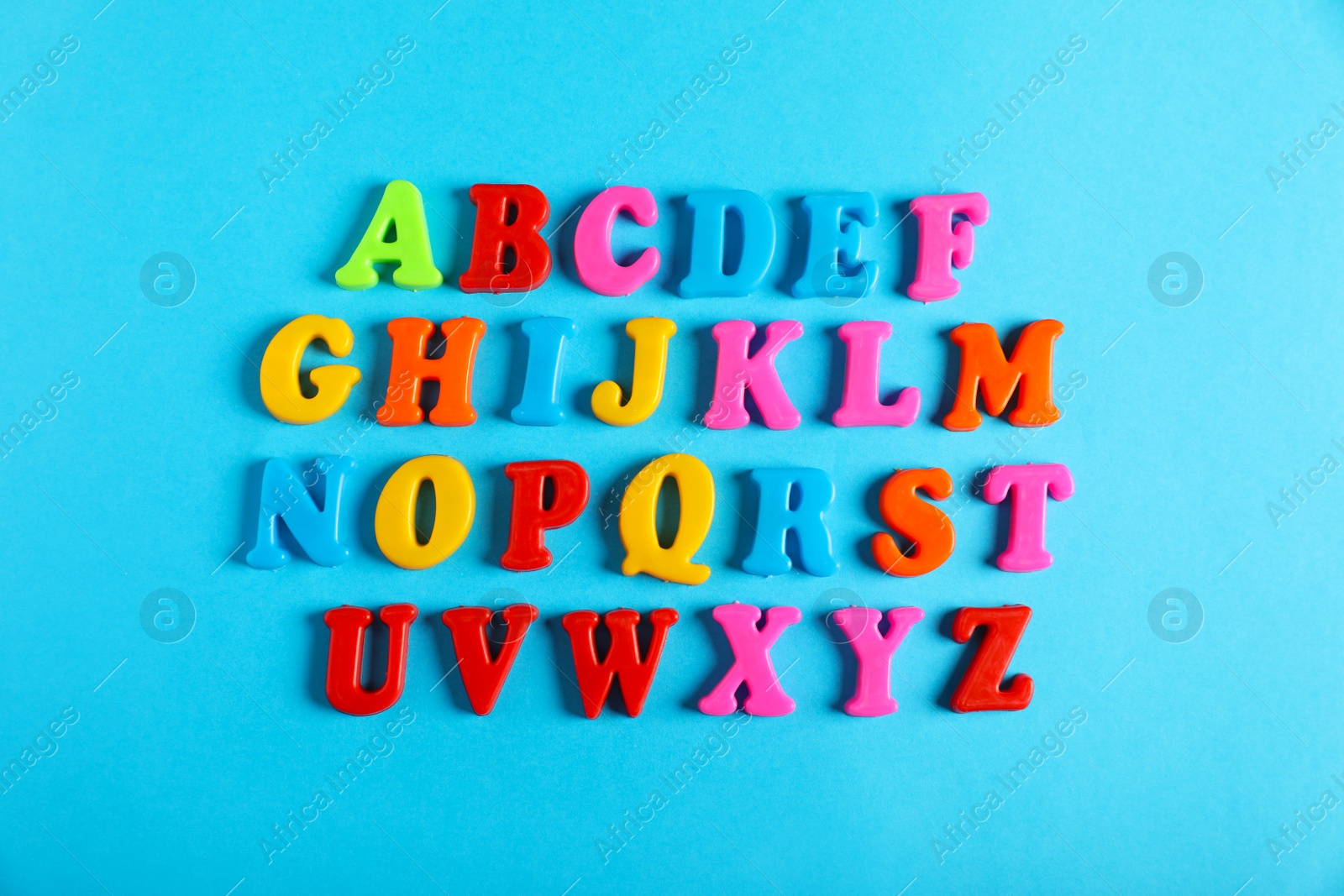 Photo of Many colorful magnetic letters on light blue background, flat lay. Alphabetic order