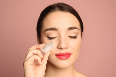 Young woman with ice cube on color background. Skin care