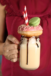 Photo of Woman with mason jar of delicious milk shake, closeup