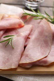 Photo of Slices of delicious ham with rosemary on table, closeup