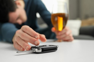 Photo of Drunk man reaching for car keys indoors, selective focus. Don't drink and drive concept