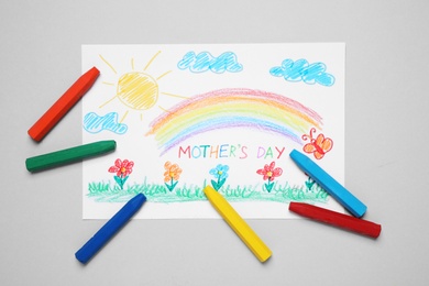 Photo of Handmade greeting card for Mother's Day and crayons on grey background, flat lay