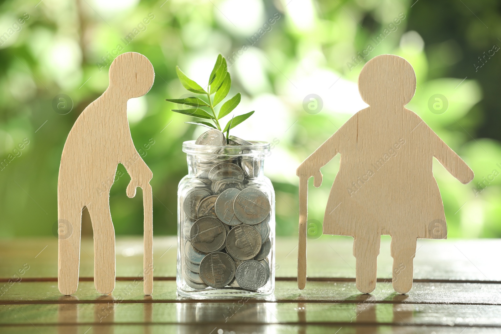 Photo of Pension savings. Figures of elderly people, coins and green twig in jar outdoors