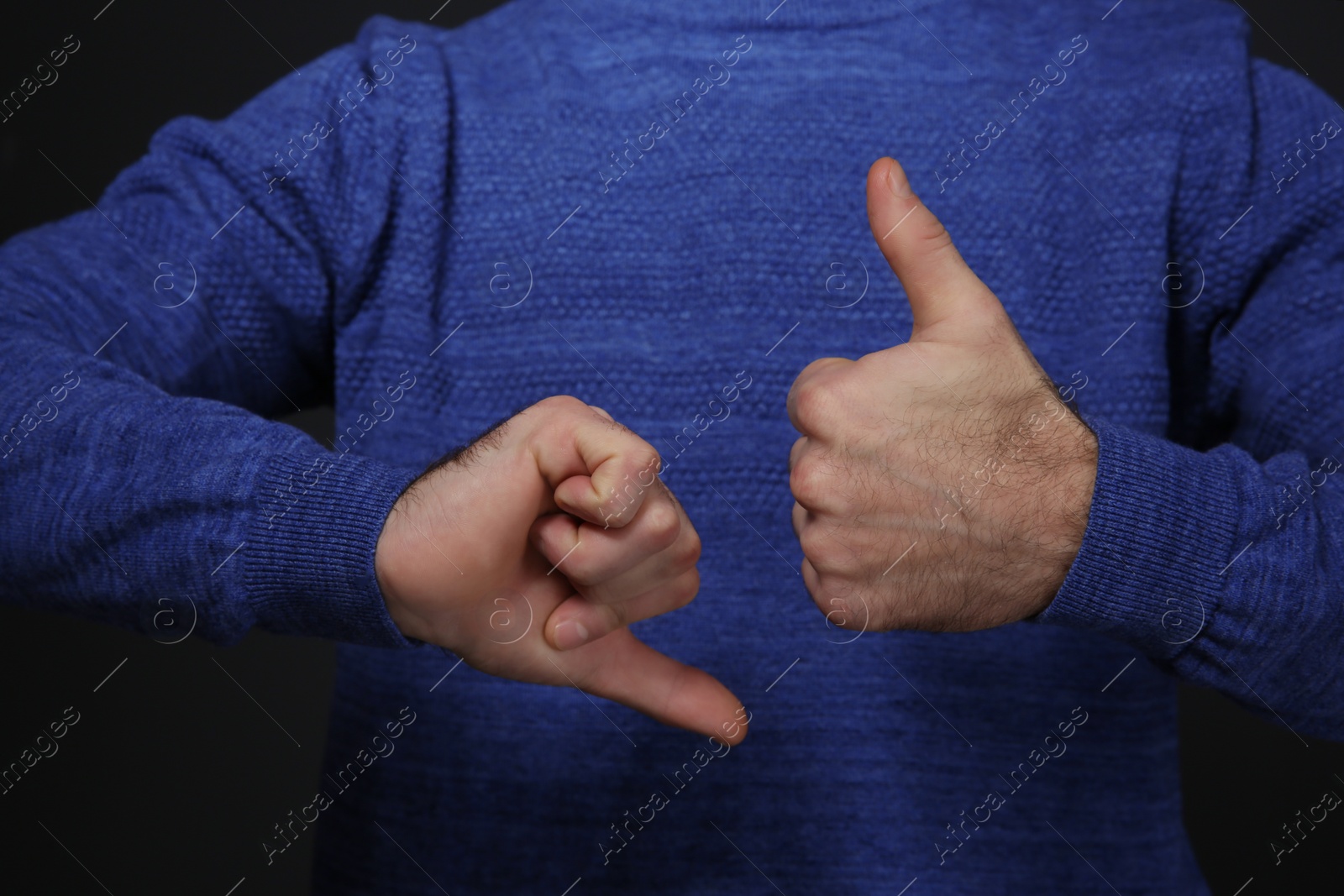 Photo of Man showing THUMB UP and DOWN gesture in sign language on black background, closeup