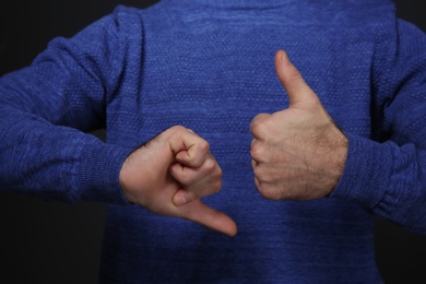 Photo of Man showing THUMB UP and DOWN gesture in sign language on black background, closeup