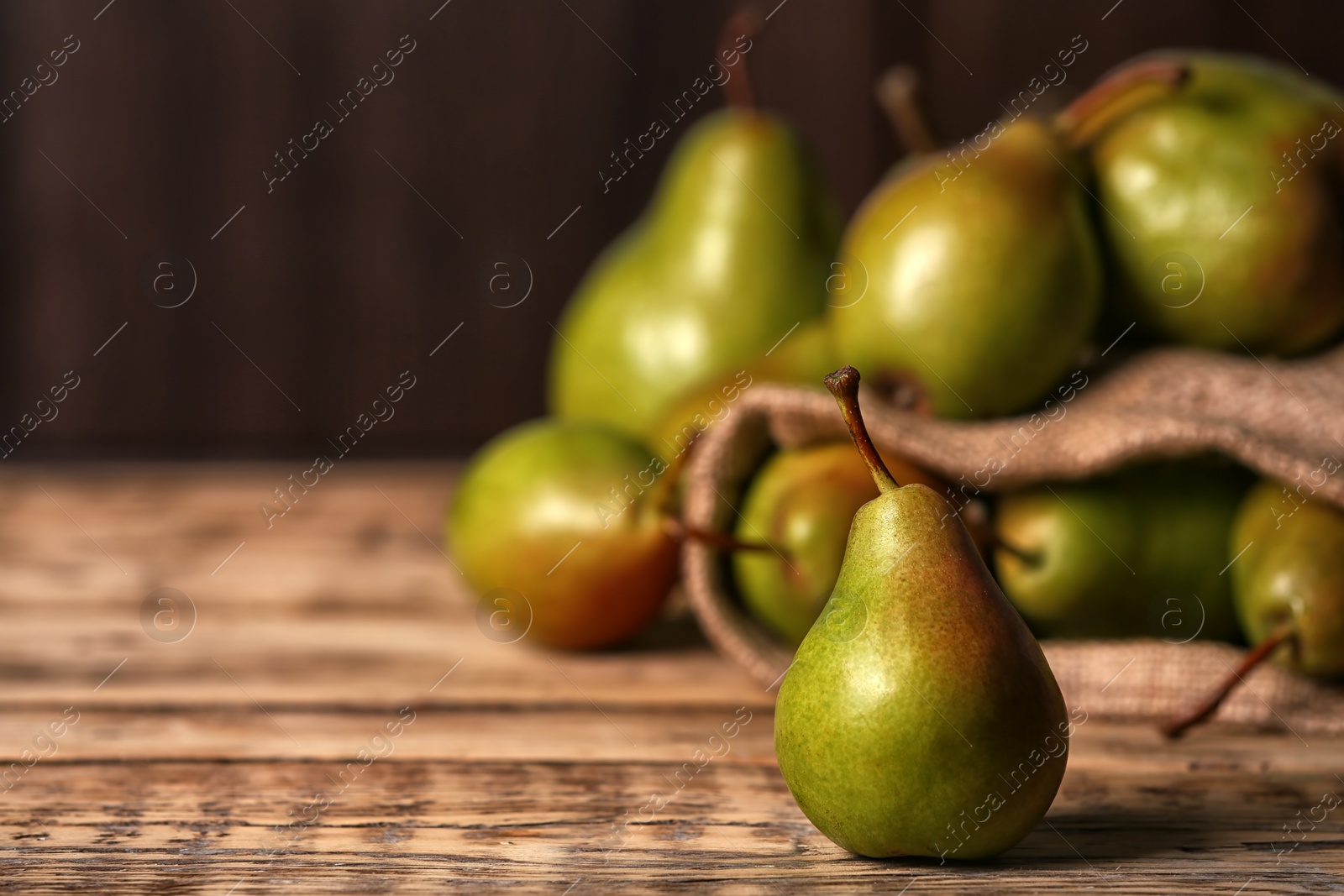 Photo of Fresh ripe pear on wooden table against blurred background