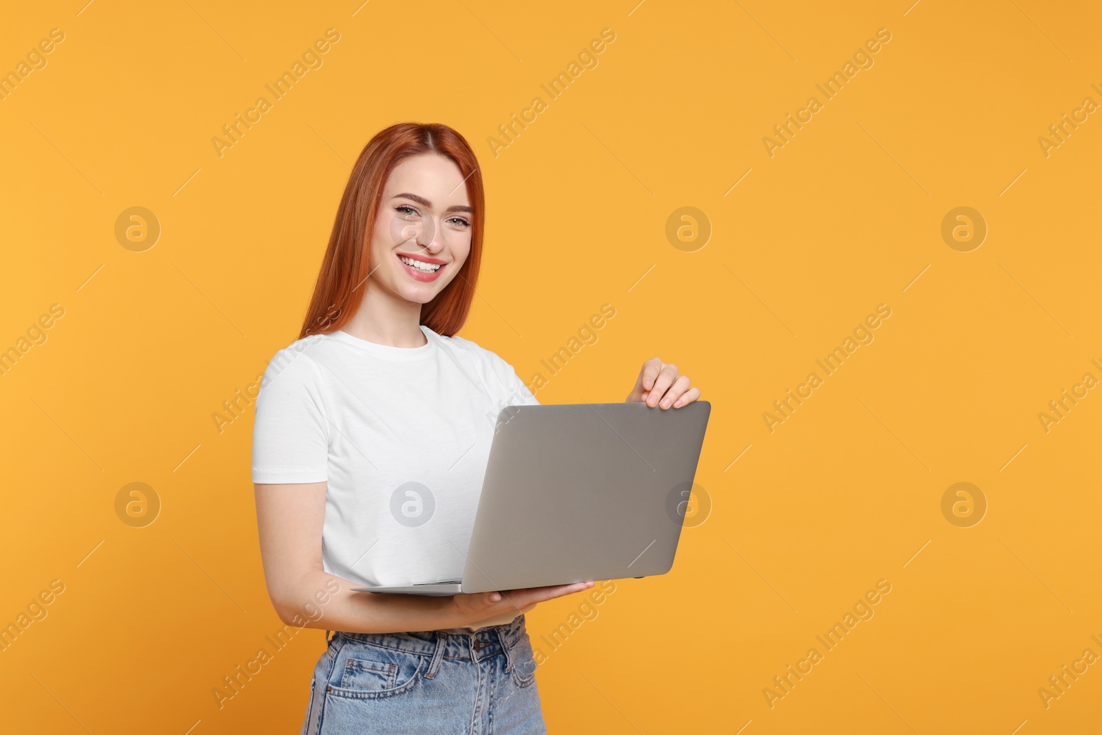 Photo of Smiling young woman with laptop on yellow background, space for text